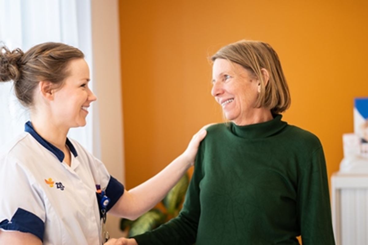 Verpleegkundige biedt steun aan vrouwelijke patient door hand op haar schouder te leggen