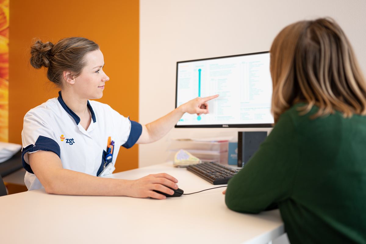 Verpleegkundige legt Lastmeter aan patiënt uit Verpleegkundige legt Lastmeter aan patiënt uit